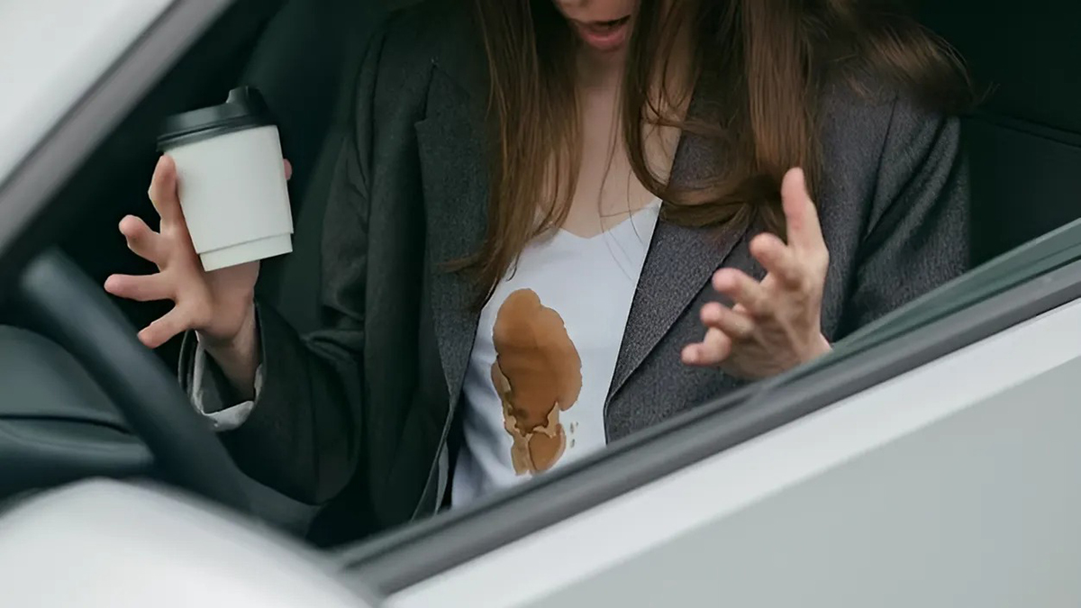 Mulher com uma mancha de café na camisola no interior do carro