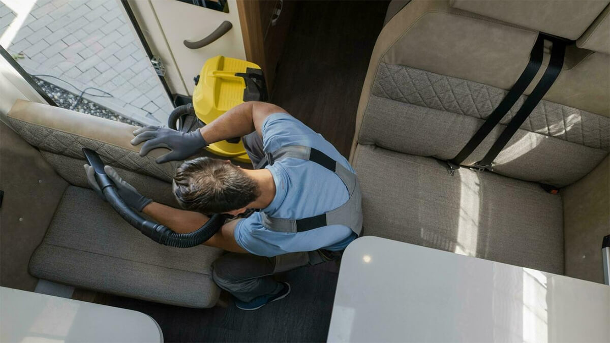 Homem a aspirar a estofaria de um banco de uma autocaravana