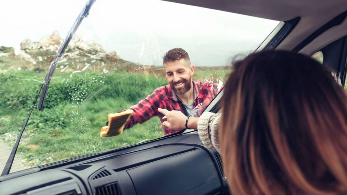 Homem a limpar o para-brisas de uma autocaravana pelo exterior
