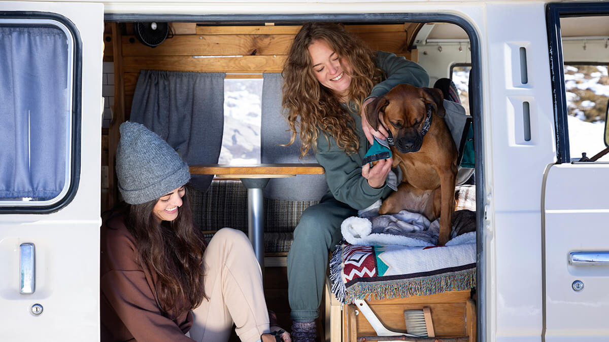 Duas mulheres e um cão no interior de uma caravana