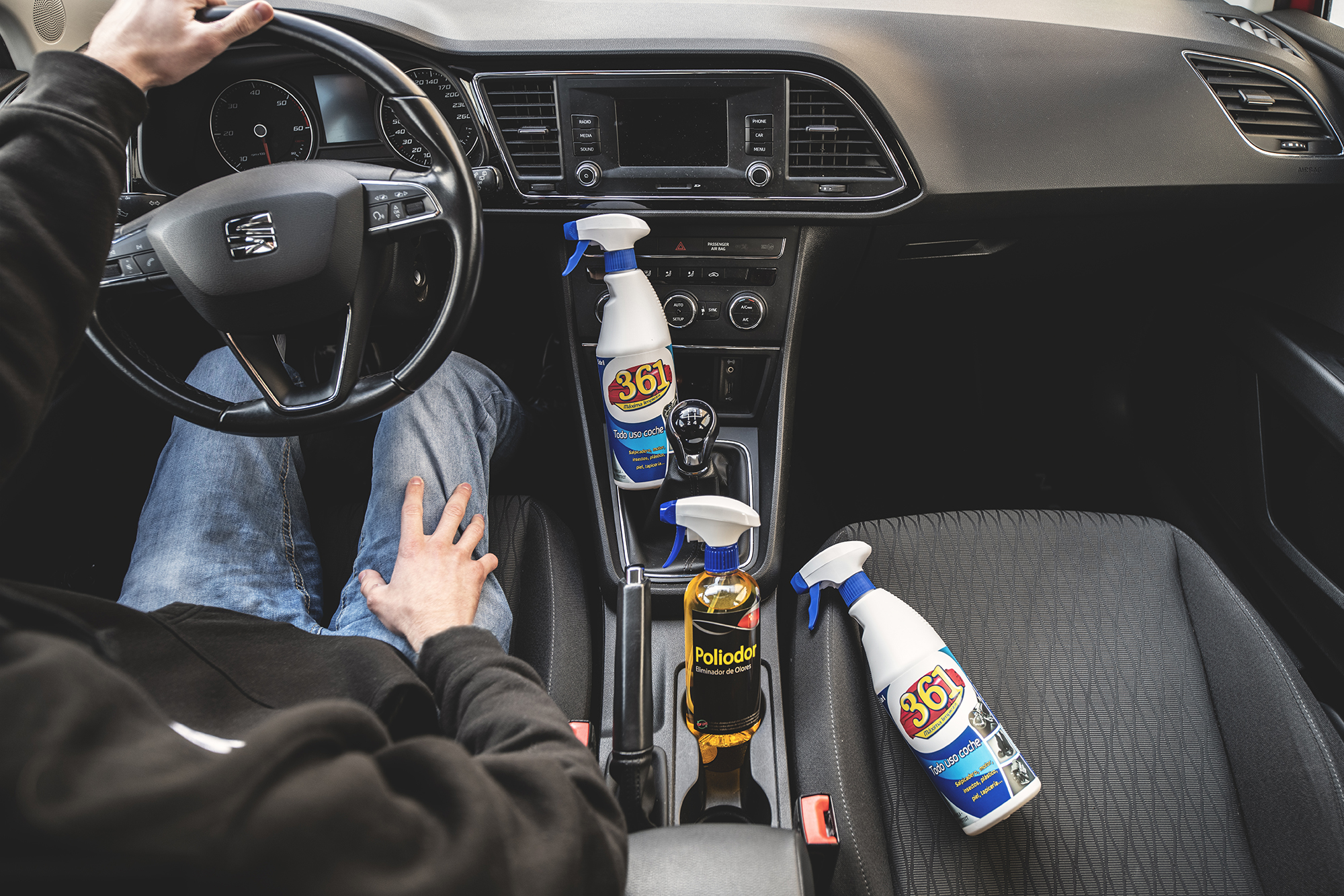 Interior de um carro Audi com um homem a conduzir enquanto no banco do passageiro estão dois 361 Todo Uso Coche e um Poliodor Eliminador de Odores