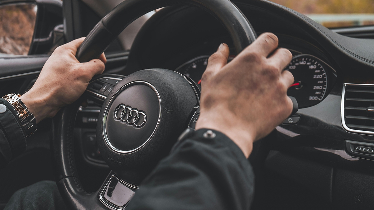 Mãos de um homem a segurar o volante de um carro Audi