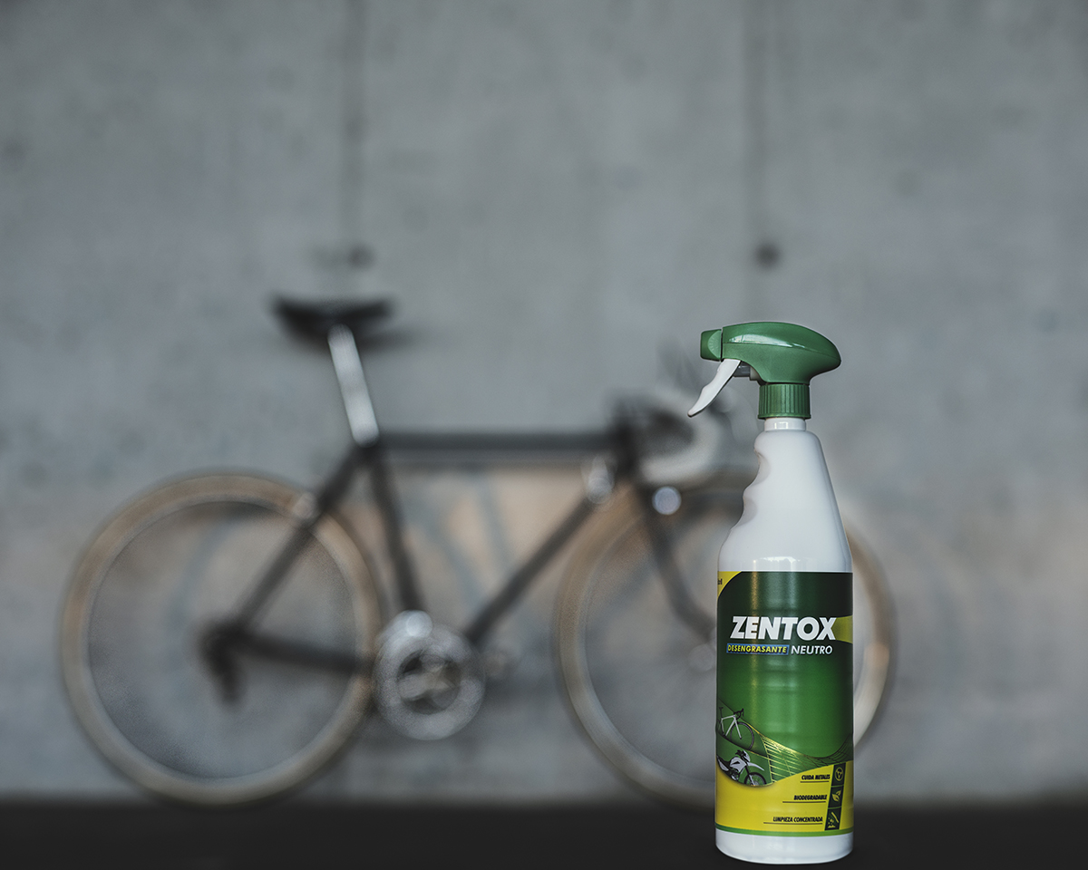 Garrafa de **Zentox Desengordurante Neutro**, com uma bicicleta em segundo plano, apoiada num muro de betão cinzento.