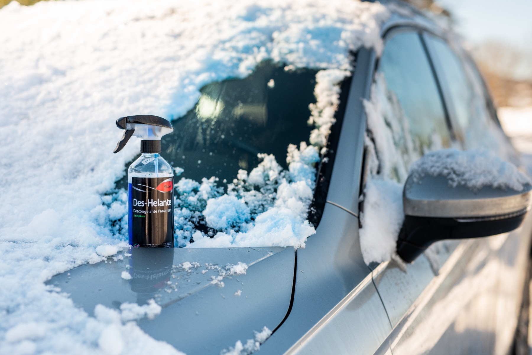 Produto descongelante de para-brisas sobre o capot de um carro nevado