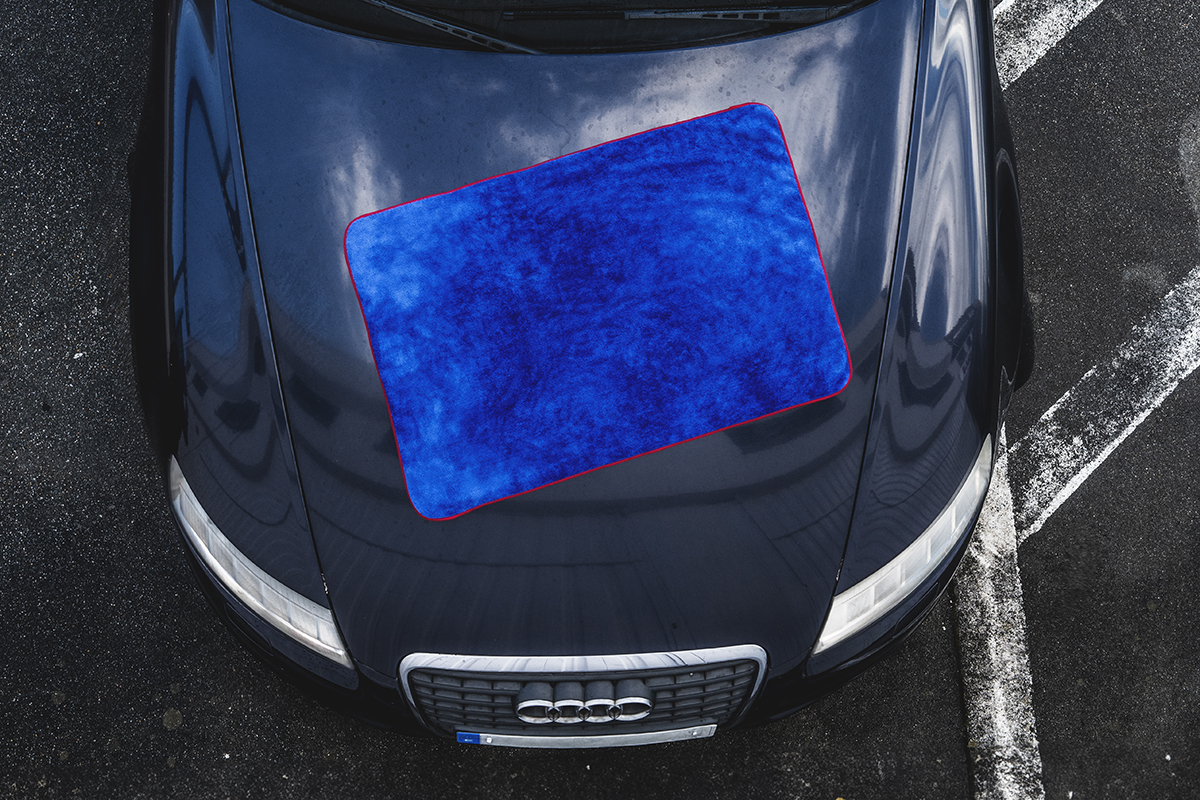 Toalha de secagem azul sobre o cap&ocirc; de um carro escuro